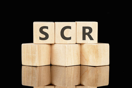 Text SCR word is made up of wooden cubes on a black background