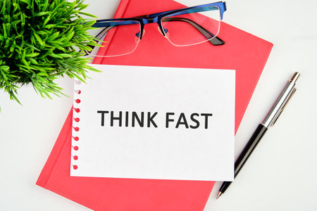 THINK FAST words written on a torn piece of paper lying on a notebook