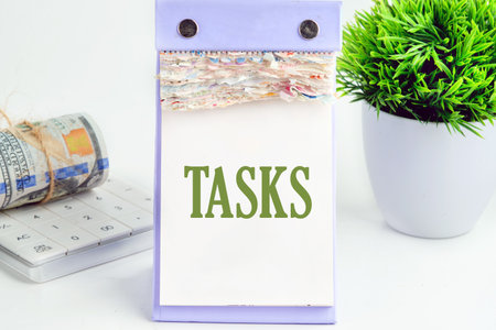 Business concept. The word Task written in a desktop calendar with dollar bills, a calculator and a...