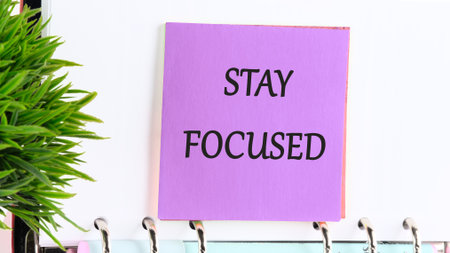STAY FOCUSED text on a purple sticker on the background of a blank sheet of a business book