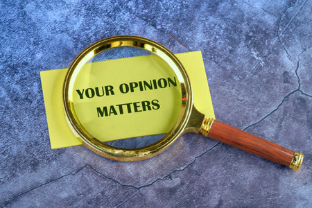 Business concept. Copy space. The text YOUR OPINION MATTERS appeared through a magnifying glass on yellow paper on an abstract backgroundの写真素材