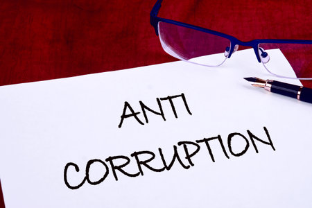 Corruption and another financial concept. ANTI CORRUPTION words on white paper on a mahogany tableの写真素材