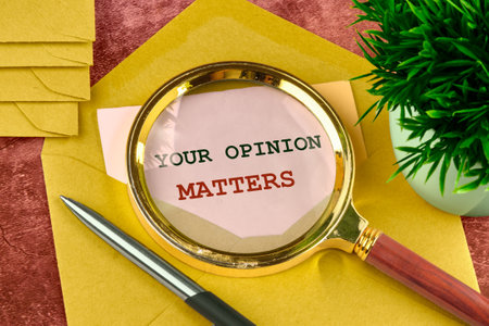 Text sign showing YOUR OPINION MATTERS through a magnifying glass in a letter peeking out of an envelopeの写真素材