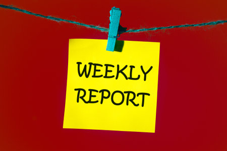 Conceptual weekly report symbol. Copy space. WEEKLY REPORT words written on a yellow sticker on a...