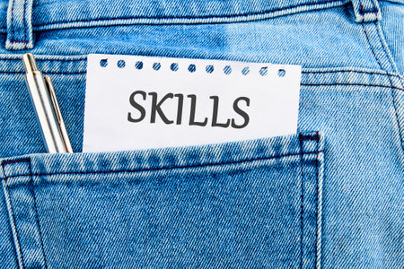 Upskilling and personal development concept. SKILLS words on a piece of paper sticking out of a jeans pocketの写真素材