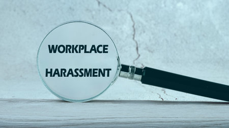 WORKPLACE HARASSMENT written through a magnifying glass on a gray backgroundの写真素材