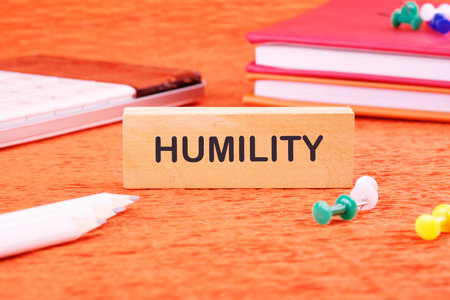 Lifestyle concept. HUMILITY word on a wooden bar in front of an orange background, front viewの写真素材