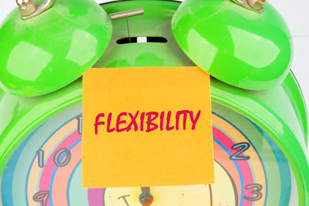 Business flexibility concept. Copy space. Flexibility symbol. Concept word Flexibility on the sticker on the background of the alarm clockの写真素材