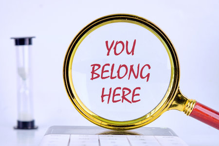 Business, diversity, inclusion, belonging and you belong here concept. Copy space. YOU BELONG HERE through a magnifying glass on a uniform light backgroundの写真素材