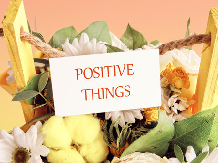 POSITIVE THINGS phrase on a white business card against a background of bouquets of flowersの写真素材