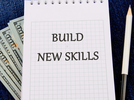 Business, education build new skills concept. Copy space. Concept word BUILD NEW SKILLS on a piece of paper on dollar billsの写真素材