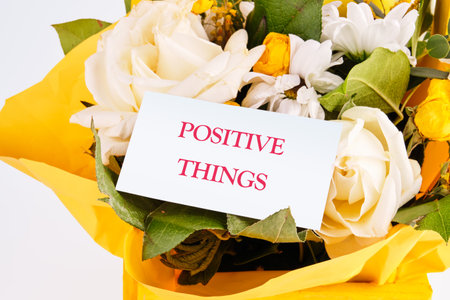 POSITIVE THINGS phrase on a white business card on the background of a bouquet of beautiful flowersの写真素材