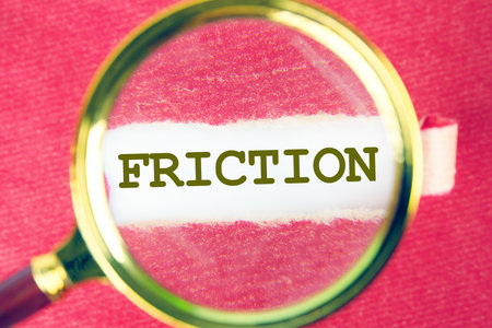 Friction concept. Friction word on white paper through a magnifying glass under a torn piece of red paperの写真素材