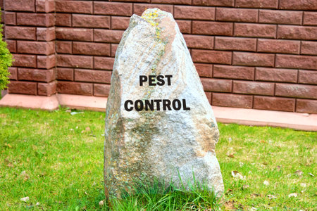 PEST CONTROL written on a stone on the background of a fence, red brick wallsの写真素材