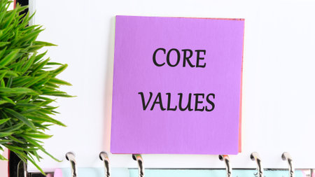 Business and core values concept on a purple sticker on the background of a white leaf and a green plant in the foregroundの写真素材