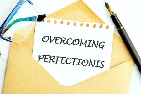 Business Overcoming perfectionism concept. Copy space. Concept words Overcoming perfectionism on a white sheet of notepad sticking out of an envelopeの写真素材