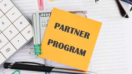 Economy and business concept. PARTNER PROGRAM on a yellow sticker on top of dollar billsの写真素材