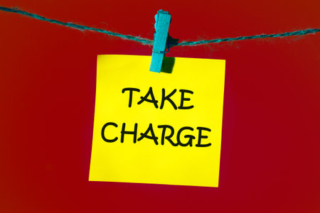 Conceptual take charge symbol. Copy space. TAKE CHARGE words written on a yellow sticker on a red backgroundの写真素材