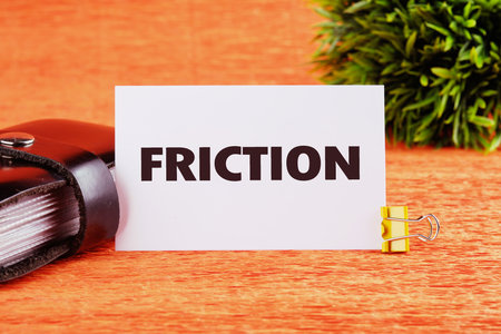 Friction concept. Friction word on a white card on an orange background, close-up, front viewの写真素材