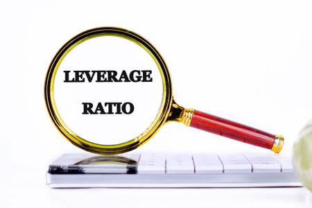 LEVERAGE RATIO text through a magnifying glass, close-up on a calculator in front of a light backgroundの写真素材