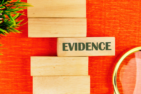 Criminal investigation and investigation Fingerprint. Evidence in criminal investigations. The conceptual phrase EVIDENCE on wooden blocks in a composition with a fragment of a magnifying glass and a plantの写真素材