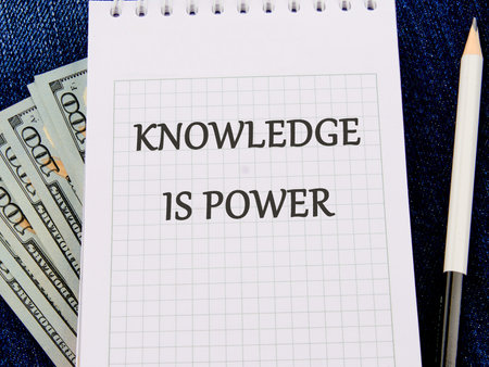 KNOWLEDGE IS POWER words on a piece of paper on dollar billsの写真素材