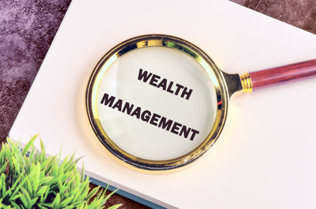 WEALTH MANAGEMENT words written through a magnifying glass in a business record bookの写真素材