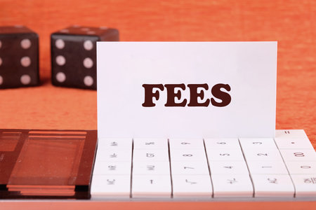 Business and finance concept. Costs, charges, commissions, penalties. Cost, fee and taxes. FEES on a white business card on the calculator, front viewの写真素材