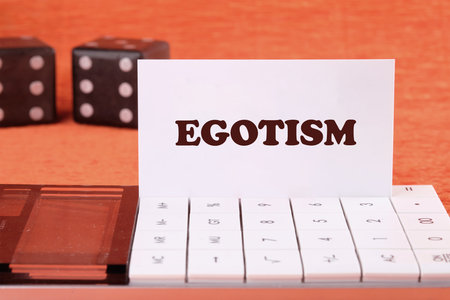 Concept image. the word EGOTISM on a white business card on the calculator, front viewの写真素材