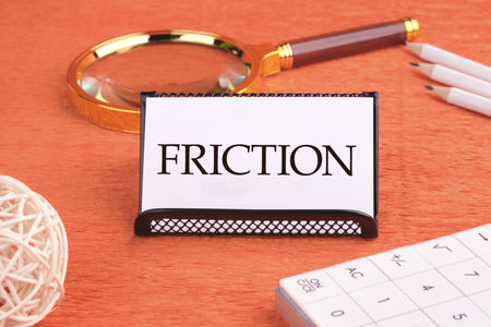 Friction concept. Friction word on a white business card, front viewの写真素材