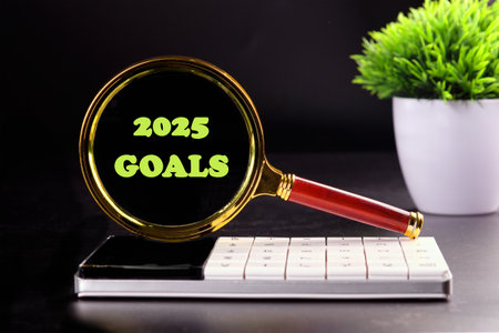 Copy space. 2025 GOALS written through a magnifying glass on a calculator on a black backgroundの写真素材