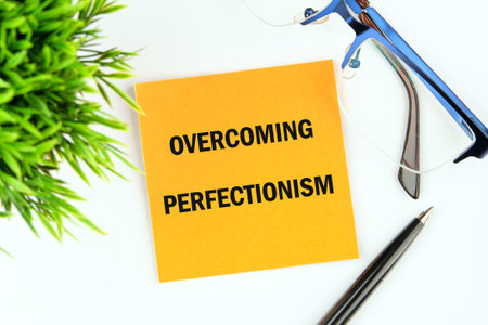 Business Overcoming perfectionism concept. Copy space. Concept words Overcoming perfectionism on a sticker on a white background, top viewの写真素材