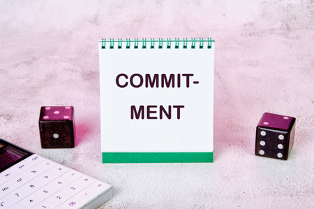 COMMITMENT Word Written on a notepad on an abstract background.