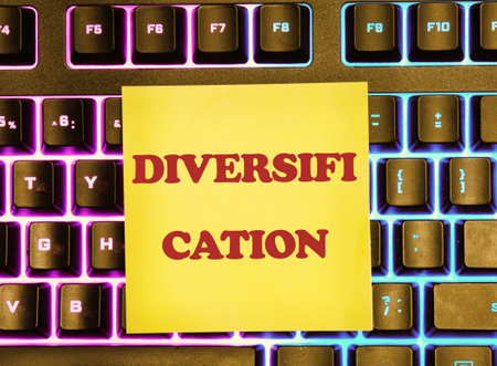 Business concept image. Word DIVERSIFICATION on a yellow sticker on the background of a glowing keyboard.の写真素材