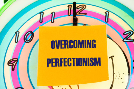 Business Overcoming perfectionism concept. Copy space. Concept words Overcoming perfectionism on the sticker on the background of the clock face with handsの写真素材