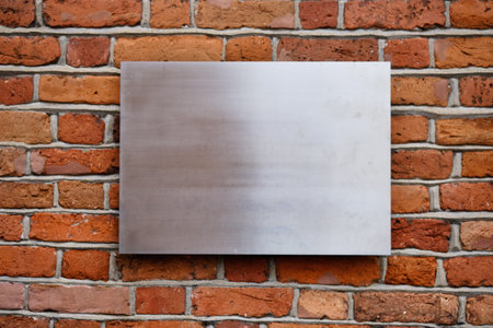 A smooth metal panel is affixed to an old brick wall, showcasing the contrast between the shiny...