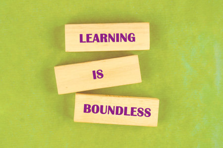 Wooden blocks display the phrase learning is boundless set on a bright green surface. This simple...