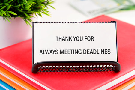 A thank you note placed on a desktop featuring vibrant colored folders. It highlights appreciation for always adhering to deadlines in a work setting.の写真素材