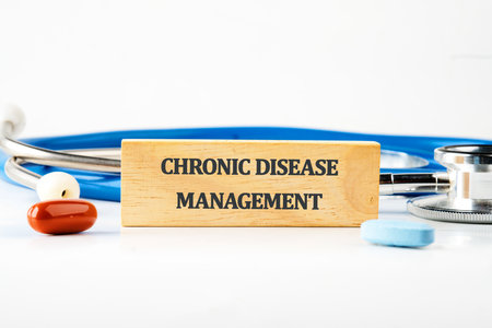 A wooden block with chronic disease management is shown with a stethoscope and pills, representing healthcare analysis and tech integration.の写真素材