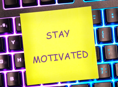 Business, support, motivation, psychological concept. STAY MOTIVATED written on a bright yellow sticker on a colorful keyboard.の写真素材