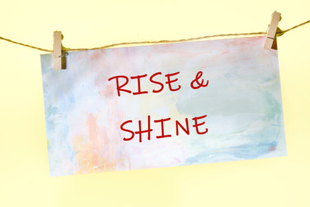 Growth Success Achievement Progress Concept. Words RISE AND SHINE written on a colorful sign on a rope with clothespins.の写真素材