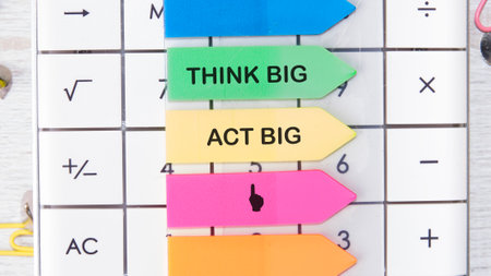 THINK BIG ACT BIG concept words motivating messages are placed on the calculator on bright stickers.の写真素材
