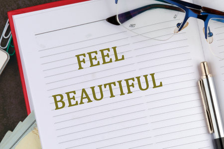 A close-up view of an open notebook with the phrase feel beautiful prominently displayed on its pages. Nearby are glasses and a pen, suggesting a personal reflection or planning session.の写真素材