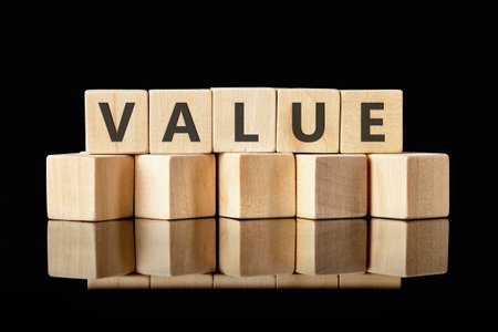 Business concept. VALUE written on wooden cubes on a black reflective surface, emphasizes simplicity and elegance.の写真素材