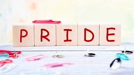 PRIDE word written on wooden blocks , and bright paper clips and buttons create an organized workspace.の写真素材