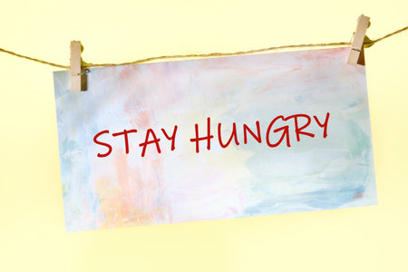 Concept Phase STAY HUNGRY written on a colorful sign on a rope with clothespins.