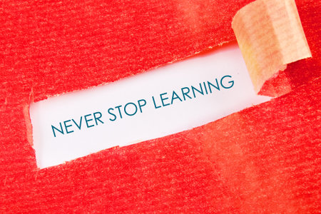 E-learning education concept. NEVER STOP LEARNING written message under a piece of torn paper.の写真素材