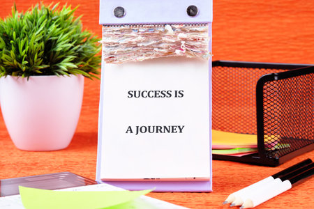 Concept text SUCCESS IS A JOURNEY written on the calendar page among the stationery.の写真素材