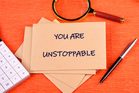 Concept text YOU ARE UNSTOPPABLE written on an envelope on a bright background, along with a magnifying glass, calculator, and pen.の写真素材