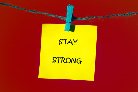 STAY STRONG message written on a bright yellow note, which is attached with a blue clothespin on a...